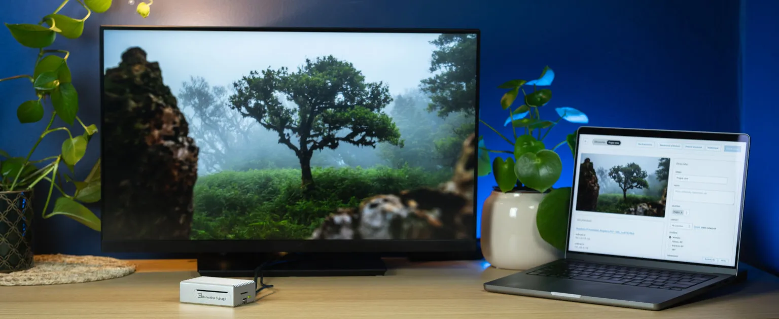 A monitor with the Bohemica Signage player and a laptop showing the screen management dashboard